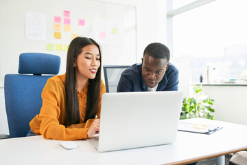 Focused team of young professionals collaborating on laptop in modern office