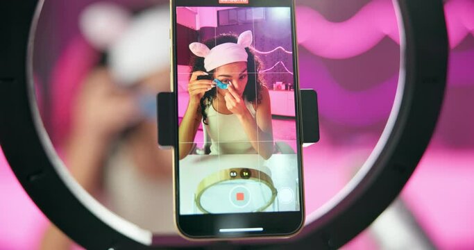Woman, cellphone and ring light for recording, screen and live streaming for cosmetic influencer in studio. Smartphone, beauty and tutorial for eye mask on social media, content creator person online