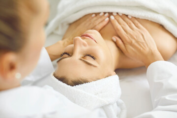 Young woman client getting good service and enjoying professional body massage at luxury spa resort wellness center. Close up beautiful calm relaxed lady customer on clean white towel on massage bed