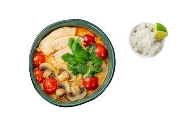 A bowl of Tom Kha soup with chicken, mushrooms, and tomatoes, served with a side of white rice and a lime wedge
