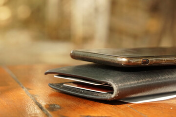 Closeup black wallet with cellphone on wood table and blurred background - business cashless 