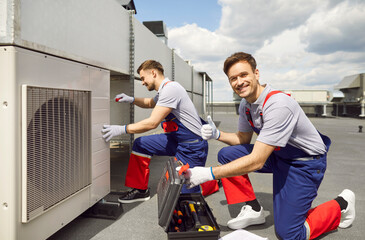 Portrait of happy smiling male worker technician wearing overall installing air conditioner and...