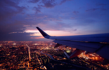 Wing of modern aircraft flying above Paris at night