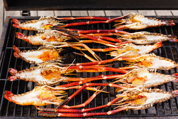 Grills king prawns on charcoal grill in the restaurant.