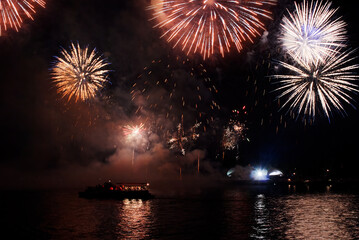 Fototapeta premium Holiday fireworks above water with reflection on the black sky background