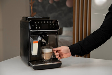 Man makes coffee on a coffee machine at home