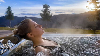 Spa on holidays. Woman relaxing in outdoor hot pool. Mountain view in winter day