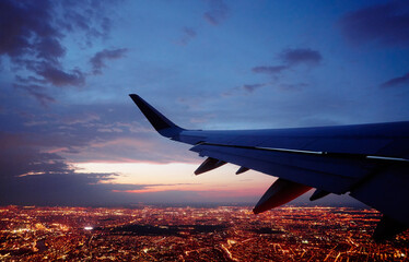 Wing of modern aircraft flying above Paris at night