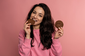 Cheerful good-looking young brunette eating her favorite oatmeal cookies during the photo shoot on...