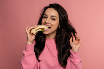 Hungry young dark-haired lady dressed in the jumper enjoying her nutritious sarnie in front of the...