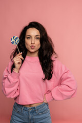 Beautiful dark-haired young lady posing with her favorite hard candy during the studio photo shoot....