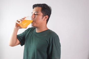 Asian adult man drinking a glass of orange juice isolated on white background