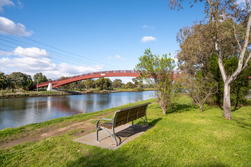 A public seating bench on the riverbank of the Maribyrnong River overlooks the Pipemakers...