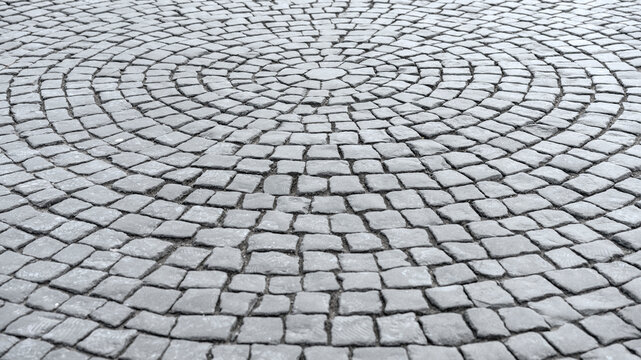 Gray cobblestone pavement arranged in intricate circular pattern. Detailed texture of stone surface highlights geometric design and traditional craftsmanship - Powered by Adobe