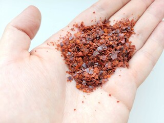 Aromatic red pepper flakes on a hand.