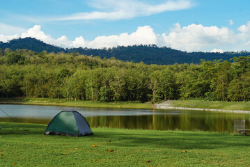 Outdoor activity concept : Travelers are camping tent in greenery season with lake background at...