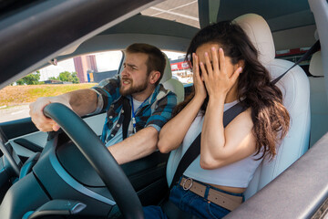 Male instructor holding steering wheel while scared woman covering her face with her hands during a driving test. Test drive, transportation, safety, education concept