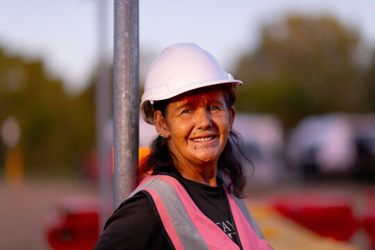 smiling mature woman outside wearing hi-vis vest and a hard hat