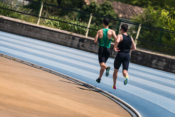 Two men run on a blue running track
