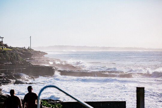 Waves crashing against Cronulla coastline rock at sunrise with sea spray