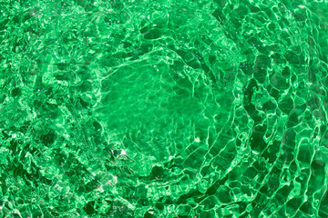 Water waves with shining design texture on a sunlight green background. Abstract background idea. Water surface concept.