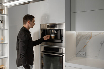 A man in a shirt prepares a latte in a built-in coffee maker
