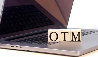 OTM word on wooden block on a laptop , business concept