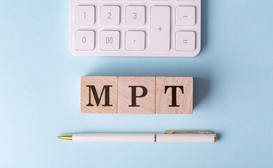 MPT word on wooden block with pen and calculator on blue background