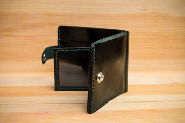 Men's wallet made of black leather on light wood, Shooting for catalog.