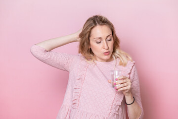 Woman holding plastic cup of water on pink background