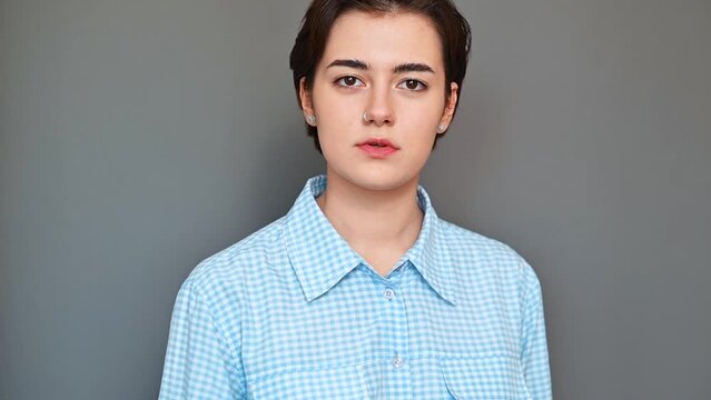 Obscene aggressive gesture, young woman showing middle finger standing on gray background