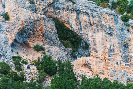 A group of people are climbing a mountain with a large rock in the background. Rodellar Huesca Spain