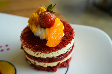Red velvet cake, classic three layered cake from red butter sponge cakes with cream cheese frosting, with mandarin orange and candied strawberry as topping American cuisine