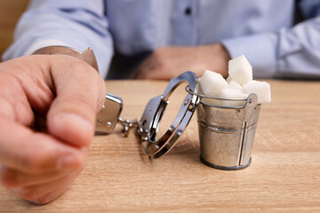 A man is handcuffed to a bucket of sugar. Sweet addiction.