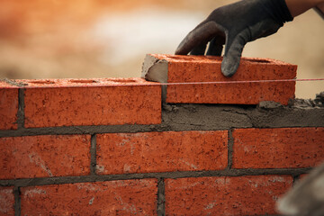 closeup of Bricklayer with Masonry Trowel laying bricks on mortar at	building site