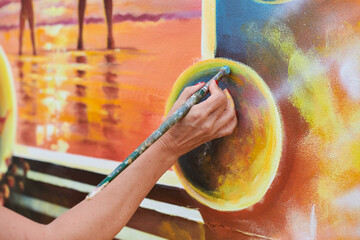 Female painter hand draws picture with paintbrush on canvas for exhibition, close up view of female...