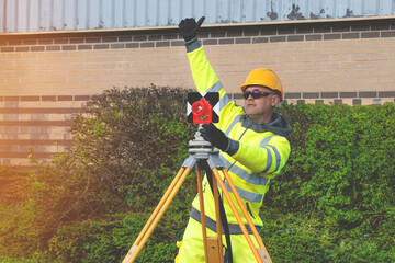 Professional Site engineer giving OK sign after installing backsight prism above control points on...