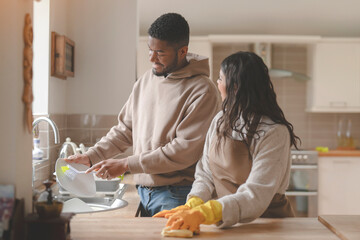 man helping woman cleaning kitchen washing dishes together at home toned image
