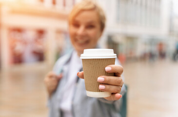 joyful woman holding craft paper coffee cup on street  in city	