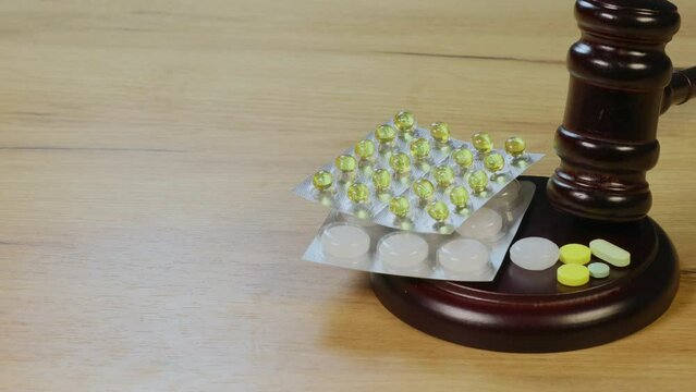 Judge gavel for adjudication with wooden stand and pills on it. 