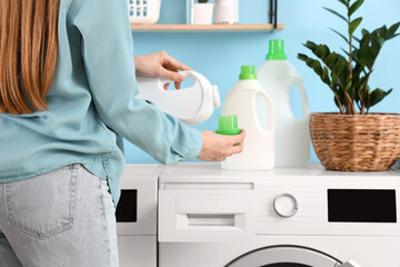 Woman pouring laundry detergent into washing machine, closeup