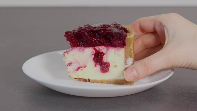 Putting a sweet dessert with cherries on the white plate. Close up.