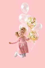 Happy jumping little girl with balloons on pink background