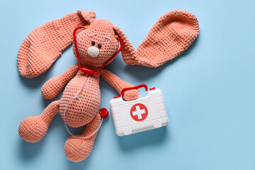 Toy first aid kit and toy bunny on blue background. Top view
