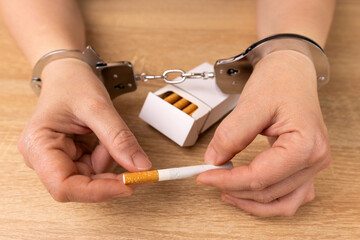 A woman is handcuffed to a pack of cigarettes. Tobacco addiction concept. It's a shame to smoke.