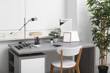 Stylish workplace with tablet computer and desk lamp in interior of modern office