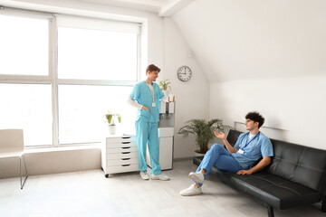 Obraz premium Male medical interns resting near cooler in clinic