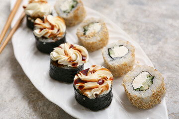 Plate with tasty sushi rolls on grey grunge background, closeup