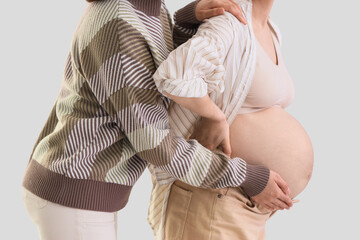 Young pregnant woman with doula on light background, closeup
