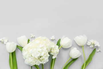 Beautiful composition with white tulips and hydrangea on grey background